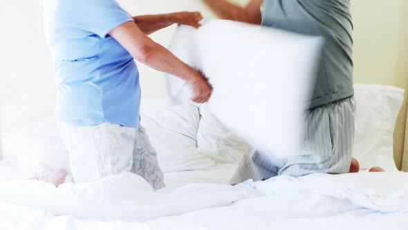 Smiling couple having pillow fight on bed