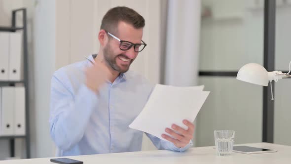 Middle Aged Man Excited By Success on Documents