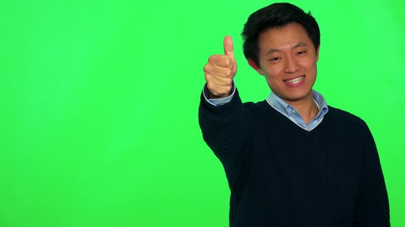 A Young Asian Man Smiles and Shows a Thumb Up To the Camera - Green Screen Studio