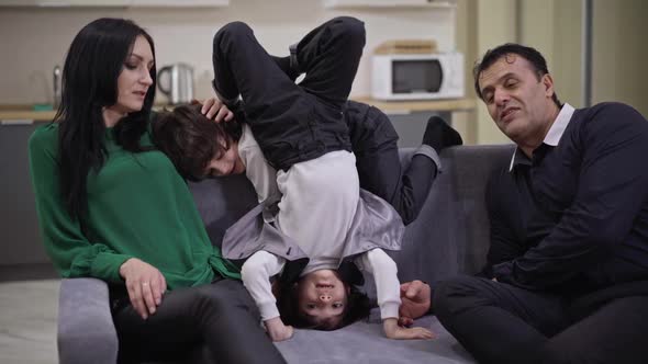 Happy Father and Mother Watching TV As Twin Sons Having Fun Grimacing on Couch