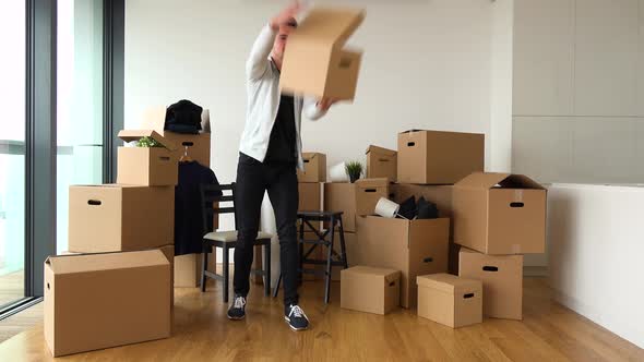 A Moving Man Catches Cardboard Boxes Thrown By Someone Off the Camera and Puts Them To the Pile