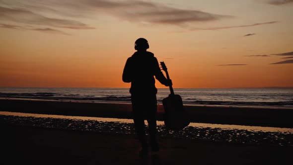 Man running with guitar in back sand beach at sunset. Beautiful, moody shots from the Sony a7iii.