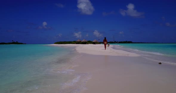 Beautiful smiling ladies on photoshoot having fun at the beach on summer white sand and blue 4K back