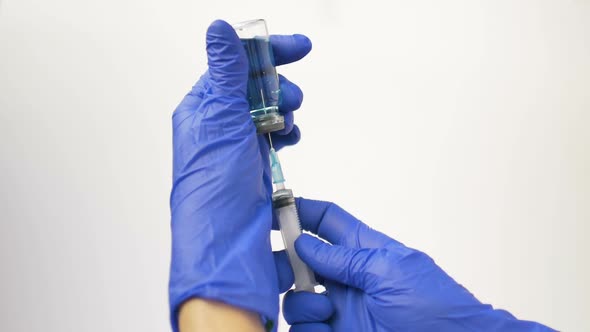 Health Worker Dials the Vaccine From Ampoule Into a Syringe Wearing Blue Protective Gloves