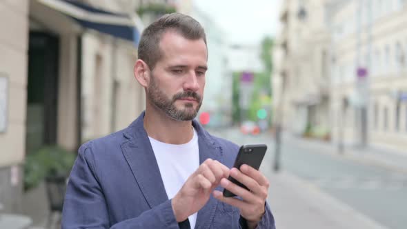 Mature Adult Man Browsing Internet on Smartphone