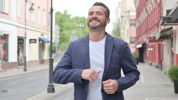 Happy Mature Adult Man Dancing While Walking Down the Street