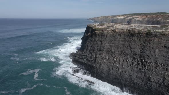 Aerial view of black cliffs in strong waves in 