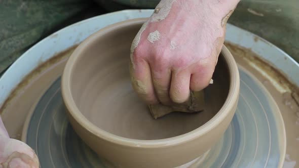 a Male Potter of Caucasian Ethnicity in a Work Shirt Makes a Bowl of Clay