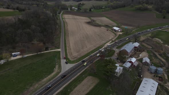 Aerial view over farm land and rural highway with rescue vehicles at an accident.