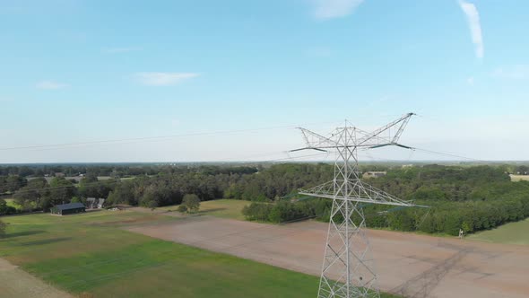 Steel lattice transmission tower pylon and power lines in countryside, aerial view