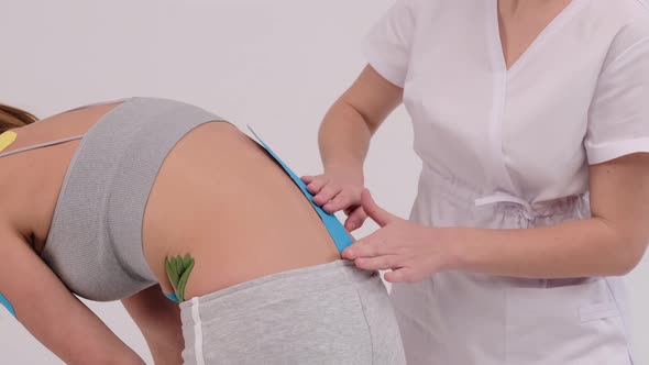 Therapist is applying kinesio tape to female back. Physiotherapy, kinesiology and recovery 