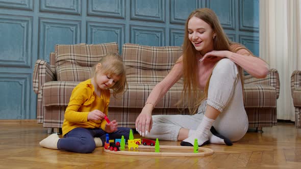 Mother Playing with Child Kid Daughter Riding Toy Train on Wooden Railroad Blocks Board Game at Home
