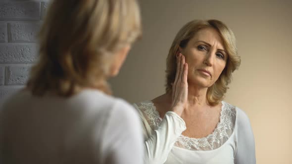 Retired Woman Sadly Looking Into Mirror, Age Appearance Problem, Wrinkles