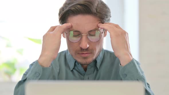 Middle Aged Man with Laptop having Headache 