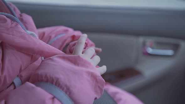 Girl Plays with Pink Winter Jacket Belt Sitting Inside Car