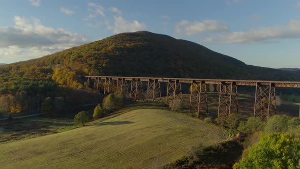 Aerial of railroad bridge passing over valley landscape on a sunny day