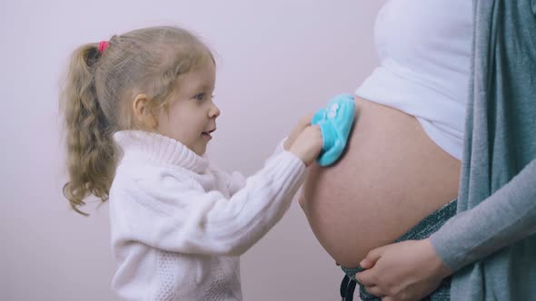 Pretty Girl Touches Pregnant Mom Belly with Blue Booties