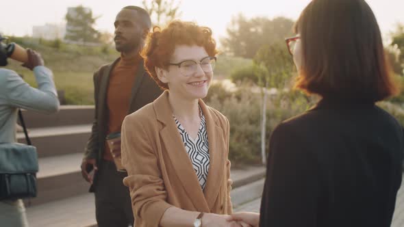 Multiethnic Businesswomen Shaking Hands and Speaking on Street