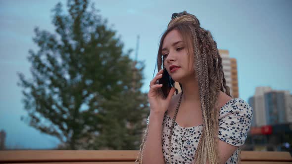 Young and Beautiful Girl Talking on a Smartphone in the Street