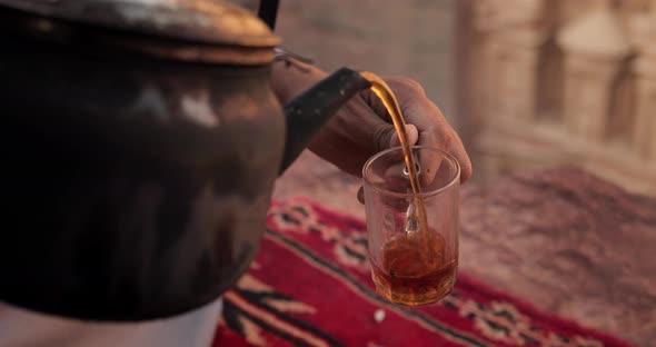 Bedouin hand pours fresh tea from a teapot in Petra's treasury, Jordan.