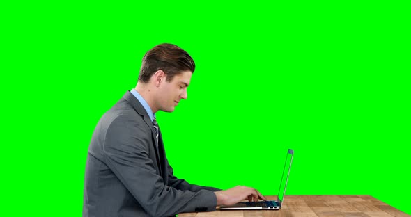 Businessman using laptop against green screen