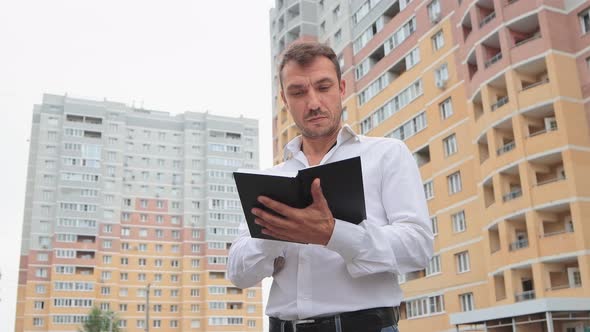 A Businessman in a White Shirt is Attentively Examining the Diary