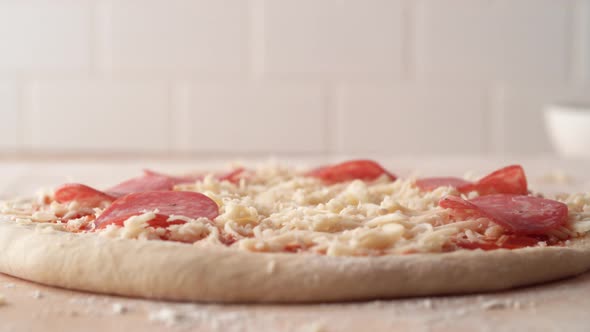 Camera follows putting a pepperoni on a pizza dough. Slow Motion.