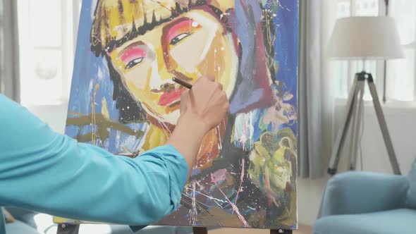 Asian Artist Man Holding Paintbrush Mixed Colour And Painting A Girl's Face On The Canvas