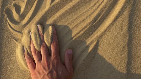 Woman's Hand Glides on the Sand in the Desert at Sunset