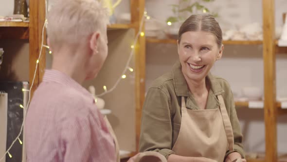 Senior Caucasian Lady Laughing with Companion during Pottery Masterclass