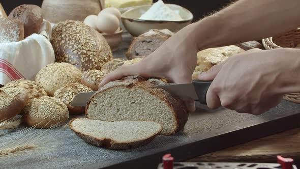 Hands Cutting the Baked Dutch Bread on the Table