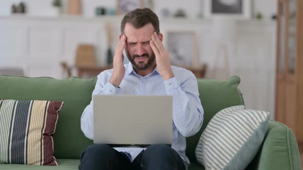 Young Man with Laptop Having Headache on Sofa