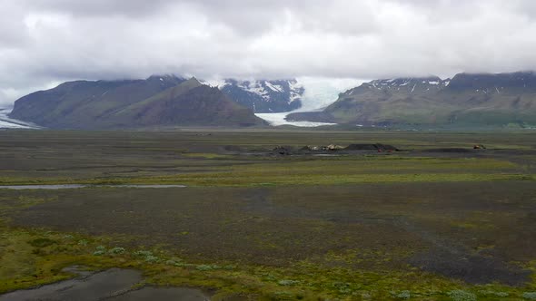 Iceland glacier wide shot with clouds and drone video moving up.