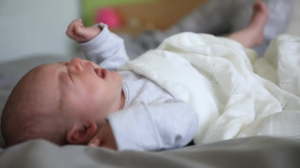 Portrait of Crying Month Baby on Grey Blanket