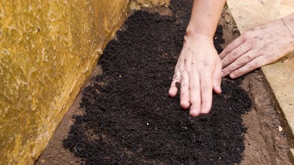 Mixing garden soil with your hands.