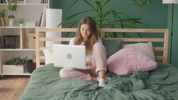 Woman Student Freelancer Studies Works Online on a Laptop at Home in Bed