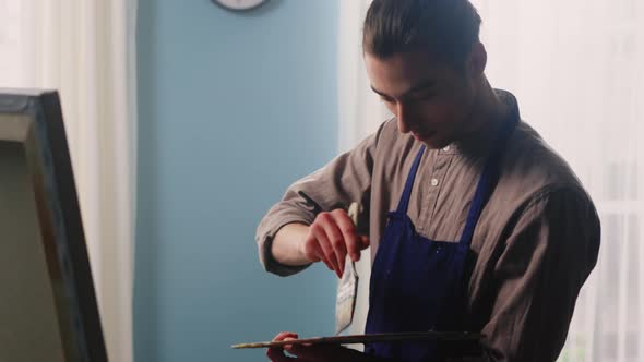 Young Man Is Mixing Paints and Drawing