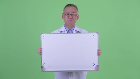 Stressed Mature Japanese Man Doctor Holding White Board