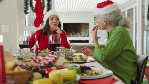 Happy caucasian adult daughter talking with mother during christmas meal