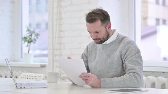 Busy Creative Man Reading Documents at Work