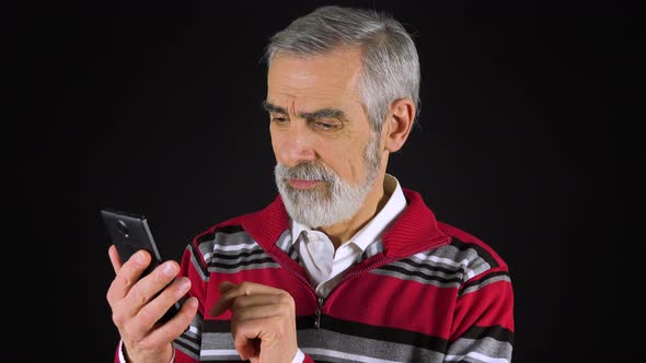 An Elderly Man Works on a Smartphone - Black Screen Studio