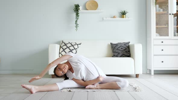 Pregnant Lady Does Janu Sirsasana Sitting on Floor at Home