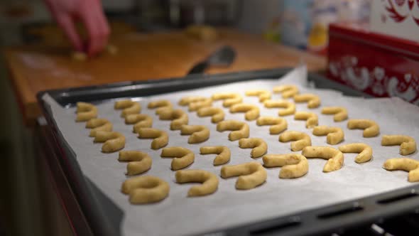 A Pan Filled with Raw Christmas Cookies, Man in the Background Cuts Dough and Makes More Cookies