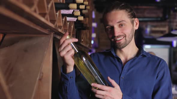 Handsome Man Holding Bottle Of Wine At Wine Cellar