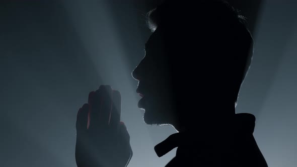 Silhouette Man Praying in Darkness alt