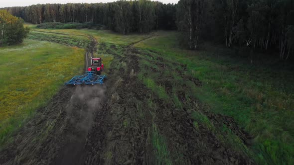 Red Tractor Plowing Field and Emitting Dust