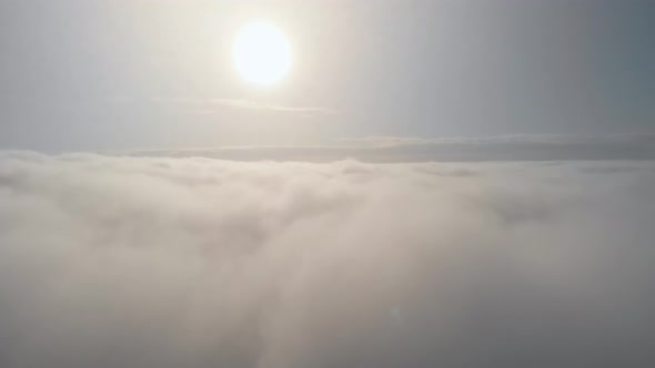 Flight Above the Clouds in an Airplane with a Bright Sun That Illuminates the Fluffy Clouds Floating