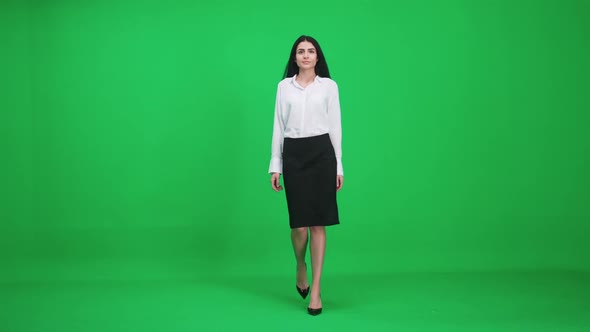 Female in a Suit Walks on a Green Background Businesswoman Comes Closer and Looks at the Camera