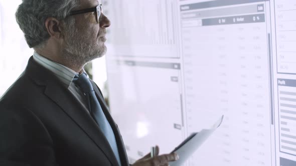 Professional Senior Businessman Standing in Front of Big Screen