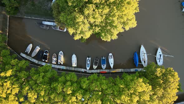 Aerial jib up shot of boats docked on canal in San Isidro city at golden hour